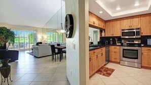 A modern kitchen with wooden cabinets, stainless steel appliances, and a dining area with a sofa and table. - Spacious-Dogs Ok-Great Views-VB887 (Palm Desert)