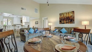 A dining area with a round table set for four, surrounded by sofas and chairs. - Great Golf Condo with Access to Resort Amenities (Palm Desert)