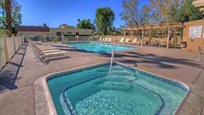 A swimming pool with lounge chairs and a pergola, surrounded by trees and a fence. - Great Golf Condo with Access to Resort Amenities (Palm Desert)