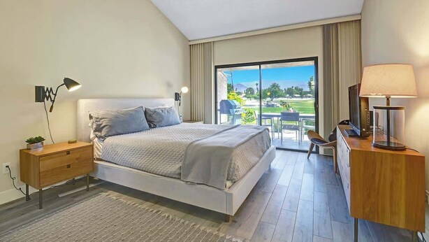 Una camera da letto moderna con un letto, comodini, una scrivania e vista sull'esterno.