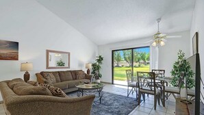 En rummelig stue med sofa, sofabord og spiseområde.