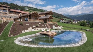 Un chalet en bois doté d’une piscine, entouré d’un jardin bien entretenu et surplombant un paysage montagneux.