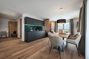 A modern kitchen with dark cabinets, a wooden dining table, and a pendant light. - Apartment Panorama with Mountain View, Sauna, Hot Tub and Wi-Fi (Mühlbach)