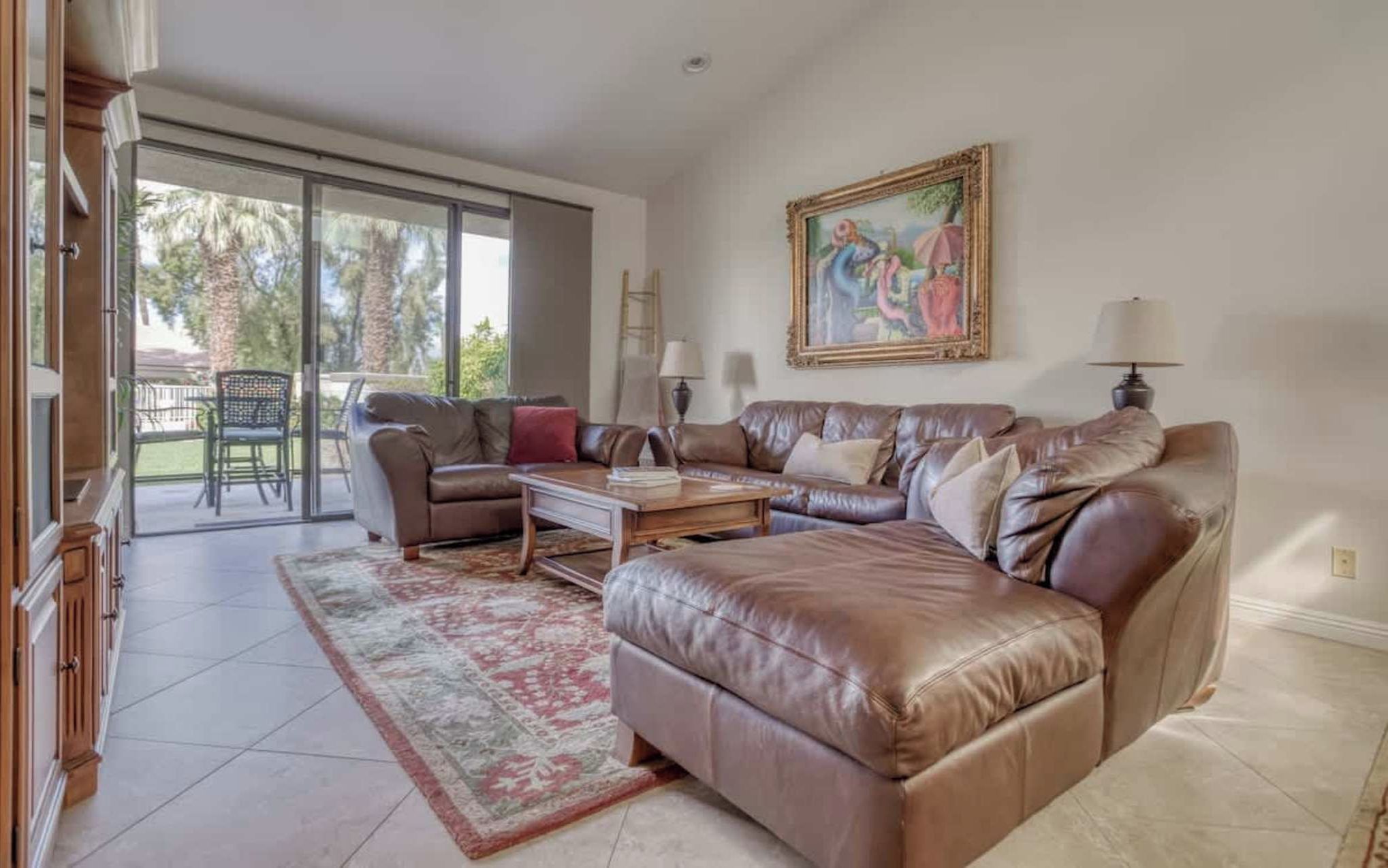Sink into plush leather seating in your spacious living room, where sunlight streams through sliding glass doors leading to your private patio. Perfect for unwinding after desert adventures.