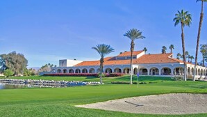 Ein Golfplatz mit einem Clubhaus, das gewölbte Gänge und ein rotes Ziegeldach aufweist.