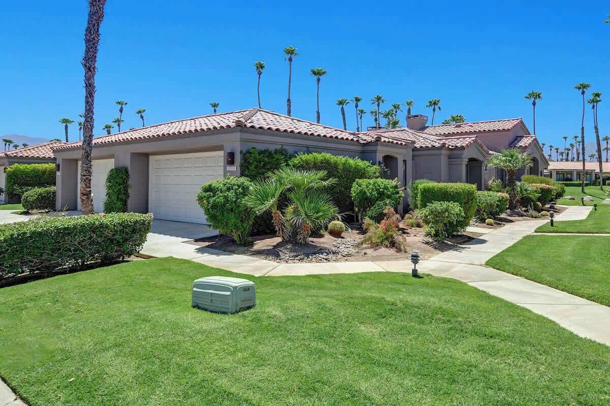 Un barrio residencial con casas de tejados de tejas, céspedes cuidados y palmeras.