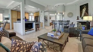 A spacious living area with a kitchen, dining area, and a large painting. - Walk to Pool and Spa-Patio-Fireplace-VB851 (Palm Desert)