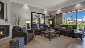 A modern living room with a fireplace, two sofas, a coffee table, and a large mirror. - Walk to Pool and Spa-Patio-Fireplace-VB851 (Palm Desert)