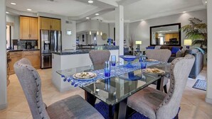 A modern kitchen with stainless steel appliances and a dining area with a glass table and chairs. - Walk to Pool and Spa-Patio-Fireplace-VB851 (Palm Desert)
