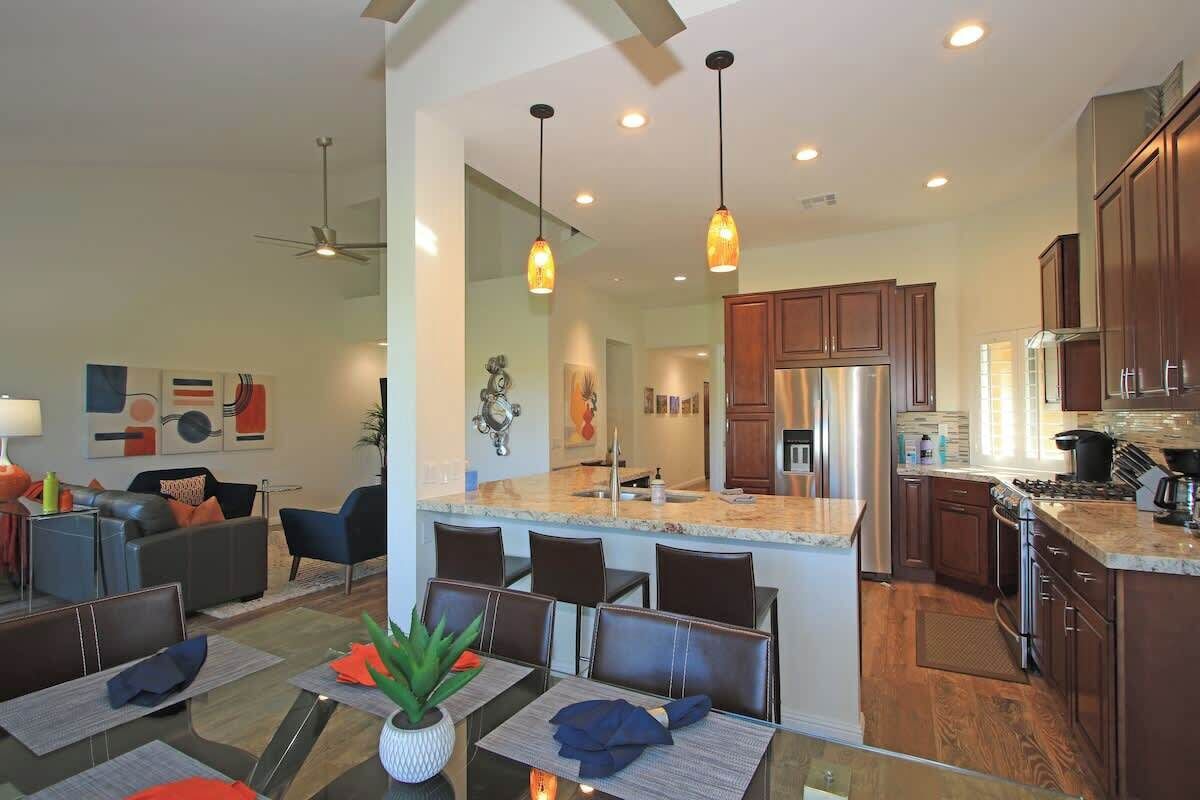 A modern kitchen with a central island, stainless steel appliances, and pendant lighting.