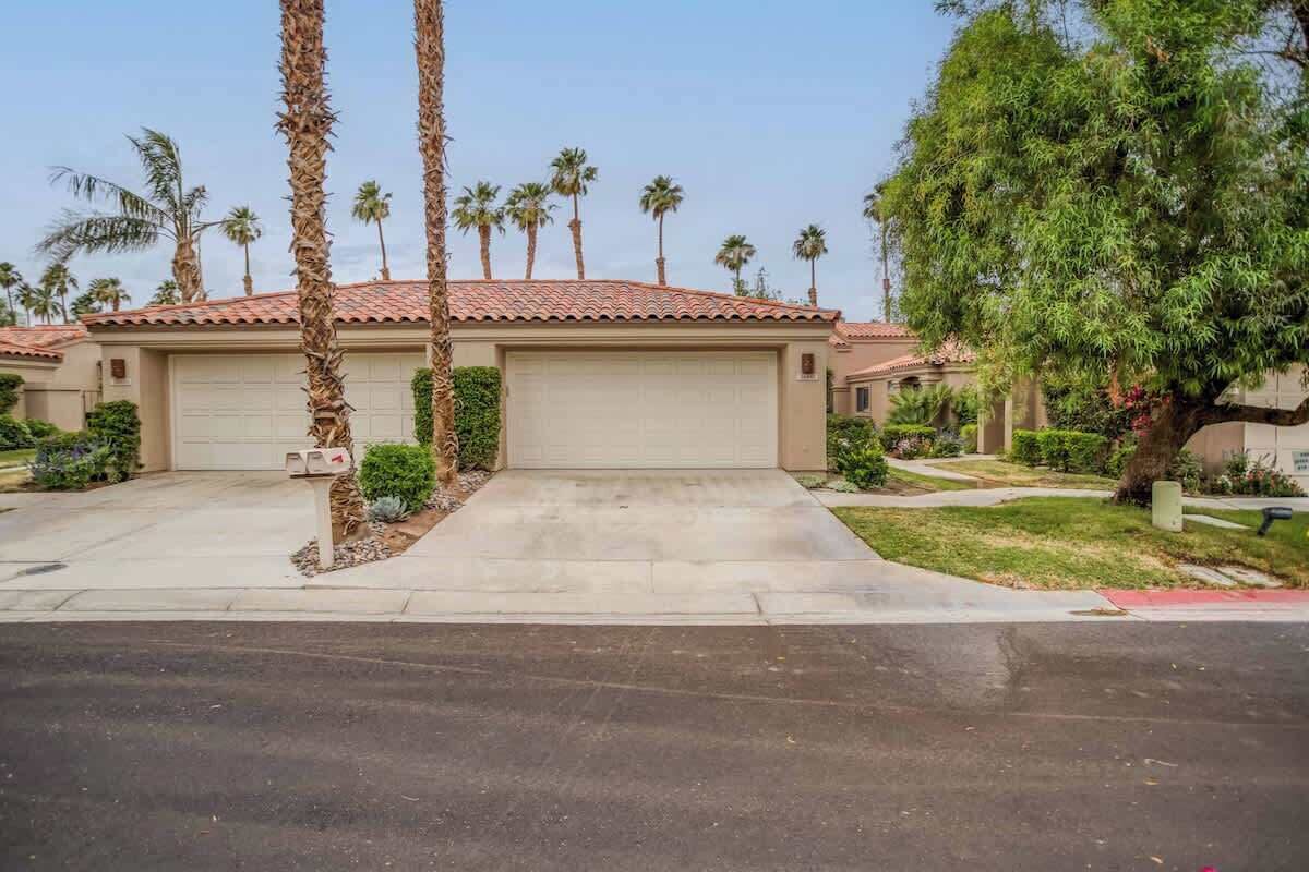 A residential house with a garage, surrounded by palm trees and a well-maintained lawn.