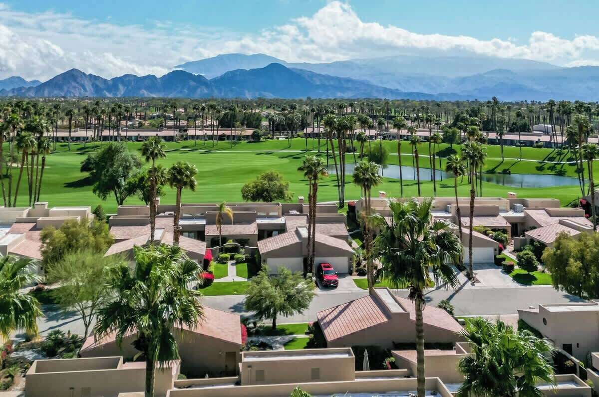 Ein Resort mit mehreren bungalowartigen Gebäuden, einem gepflegten Golfplatz und einer Bergkulisse im Hintergrund.