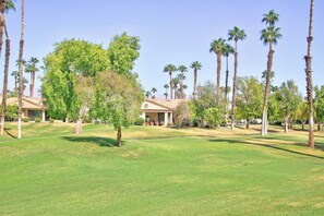 The property is situated on lush landscaped grounds featuring mature palm trees and expansive green lawns, providing a tranquil desert oasis setting. - Large-Spacious-Fitness Room-Close to Pool-V3859 (Palm Desert)