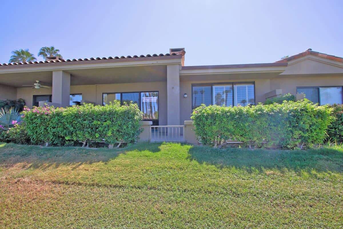 A two-story house with a covered patio, large windows, and a well-maintained garden.