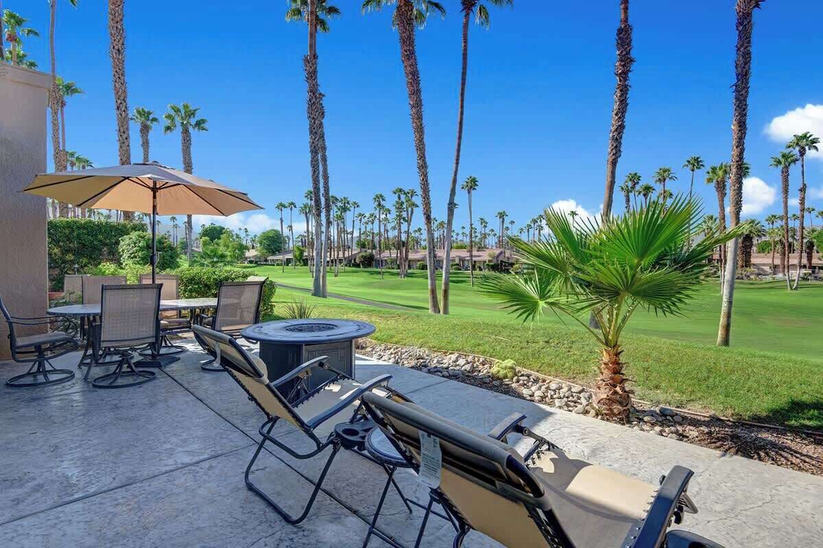 An outdoor patio with a grill, seating, and a view of a golf course.