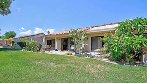 A two-story house with a tiled roof, a covered patio, and a well-maintained lawn. - Condo with views, BBQ|Pool, golf, tennis access (Palm Desert)