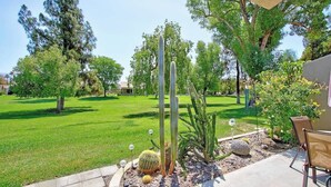 A well-maintained garden with cacti, a lawn, and a patio area with chairs. - Condo with views, BBQ|Pool, golf, tennis access (Palm Desert)