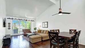 Un salón amplio con un sofá grande, una mesa de comedor con sillas y un ventilador de techo.