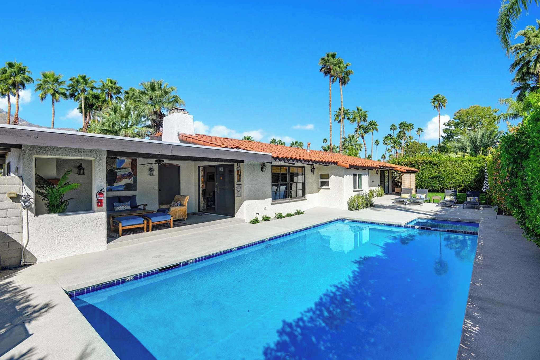 Palm-shaded oasis with sparkling pool and expansive patio framed by mountain views—perfect for sunny days and warm desert nights.