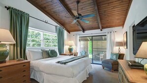 A bedroom with a large bed, wooden ceiling beams, a ceiling fan, and a sliding glass door leading to an outdoor area. - Centrally located and pet-friendly home with pool (Palm Springs)