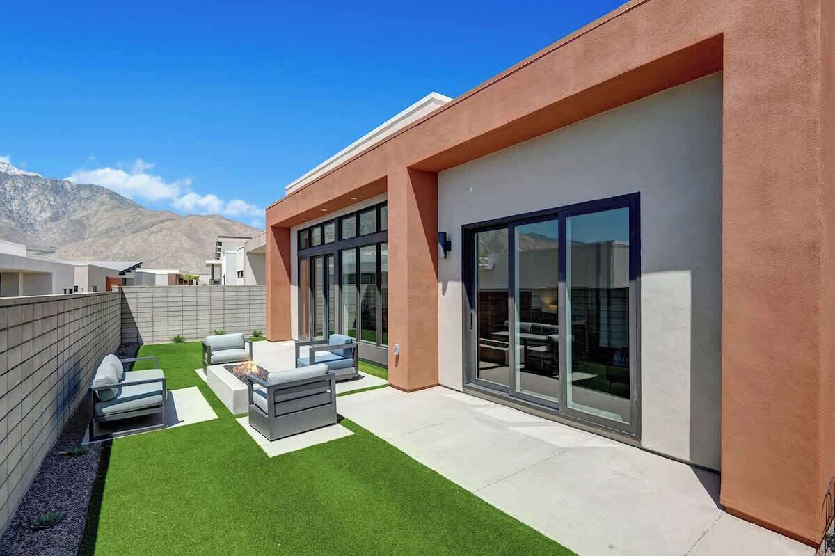 Een modern gebouw met een terras en tuinmeubilair, met een verzorgd gazon.