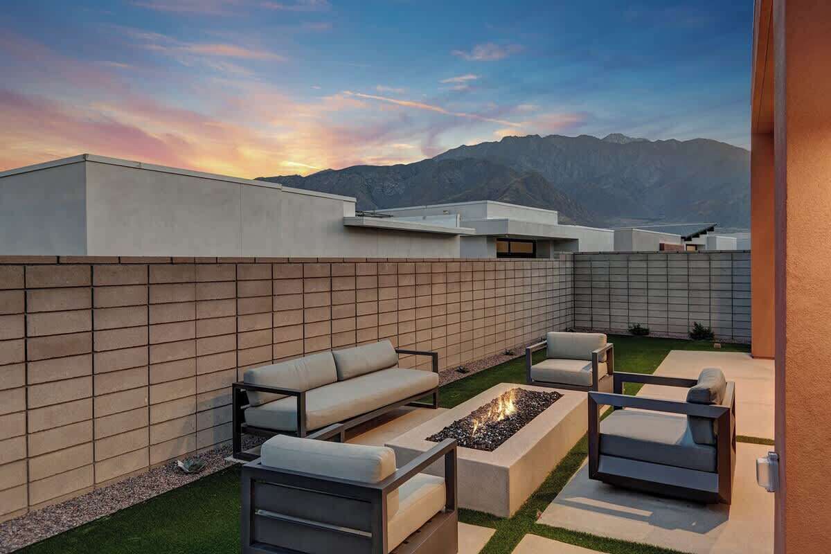 Une terrasse extérieure moderne, dotée d’un foyer, de sièges et offrant une vue sur les montagnes.