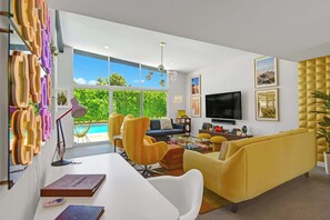 A modern living room with a pool view, a TV, and a yellow sofa. - Dog-Friendly Stunner|Pool|Fireplace|BBQ and more (Palm Springs)