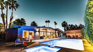Un hôtel moderne doté d’une piscine, d’un espace extérieur aménagé et de palmiers.