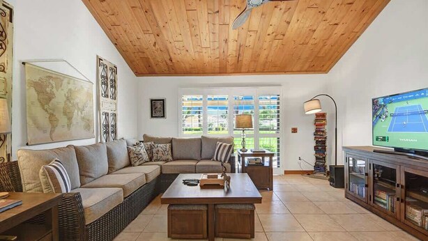 Ein Wohnzimmer mit Holzboden, einem großen Sofa, einem Couchtisch, einem Fernseher und einem Bücherregal.