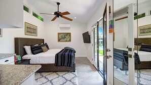 Une chambre d’hôtel équipée d’un lit, d’un ventilateur de plafond, d’une télévision et d’un grand miroir.