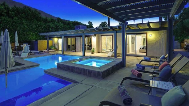 Un espace piscine extérieur moderne, doté de chaises longues et d’un coin salon abrité.