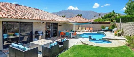 The property features a Spanish-style exterior with terra-cotta tile roofing, positioned in a desert mountain setting with palm trees and natural landscaping.