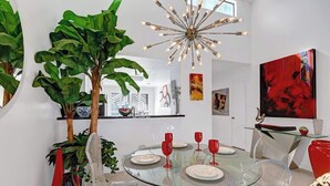 A modern dining area with a glass table, clear chairs, and red wine glasses. - Condo with Golf Course Views (Palm Desert)