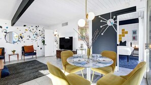 A modern living room with a round table, yellow chairs, a TV, and a decorative wall. - Retro Mid-Century Modern Retreat at Historic Ocotillo Lodge (Palm Springs)