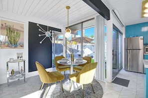 Step into your bright, open dining area where mid-century modern style meets comfort. Gather around the elegant table, soak in natural light through expansive windows, and enjoy effortless indoor-outdoor living with direct patio access. - Retro Mid-Century Modern Retreat at Historic Ocotillo Lodge (Palm Springs)