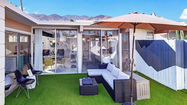 A modern outdoor patio with a white sofa, black chairs, and a large umbrella. - Retro Mid-Century Modern Retreat at Historic Ocotillo Lodge (Palm Springs)
