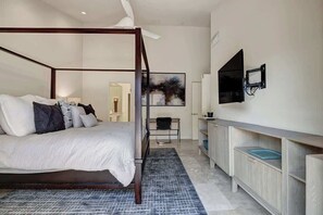 Un dormitori modern amb un llit amb cortines, un televisor de pantalla plana muntat a la paret i un taulell petit amb una cadira.