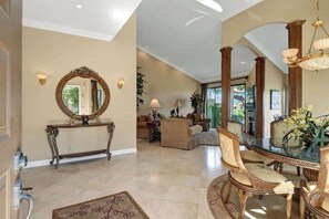 A spacious living area with a glass dining table, elegant chairs, and a large mirror on a console table. - Golf Front Condo, Fireplace, Community Pools (Palm Desert)
