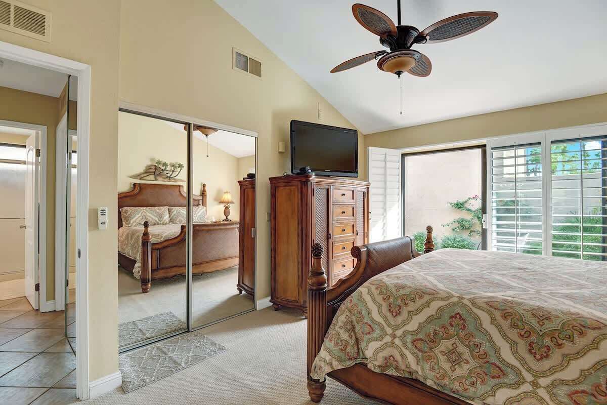 A bedroom with a bed, a dresser, a television, and a ceiling fan.