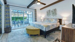 A bedroom with a bed, a desk, a chair, a window, and a ceiling fan. - Pet Friendly Bungalow in Mesquite Country Club (Palm Springs)