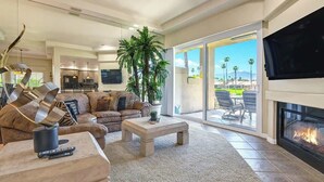 A spacious living room with a fireplace, a large television, and a view of the outdoors. - Spacious Condo|Great Views|Platinum Membership (Palm Desert)