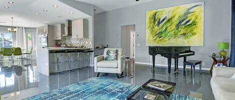 Step into an airy, light-filled space where art and comfort blend effortlessly. Let the vibrant rug and grand piano set the tone for your creative escape, while the open kitchen invites you to gather and unwind.
