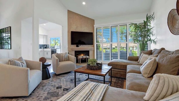 A modern living room with a fireplace, large windows, and a flat-screen TV. - Pet Friendly|2 Suites+ guest room|Large Patio|Fairway Views (Palm Desert)
