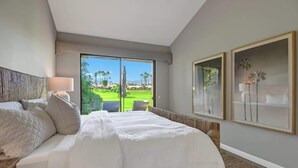 A hotel room with a large bed, a view of a golf course, and framed artwork on the wall. - Fairway View Escape in Palm Desert (Palm Desert)