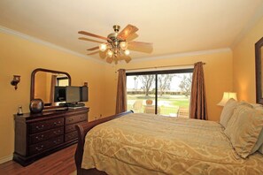 Your peaceful bedroom retreat features elegant wood furnishings and a ceiling fan to keep you comfortable, with sliding glass doors opening to a private patio overlooking lush golf course greens. - Two Bedroom Holiday Home (Palm Desert)