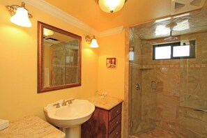 A beautifully appointed bathroom with elegant fixtures, warm lighting, and a spacious walk-in shower featuring marble-inspired tile and a rain showerhead—your serene retreat after exploring the area. - Two Bedroom Holiday Home (Palm Desert)