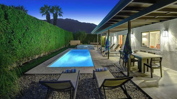 A swimming pool with lounge chairs and a table, surrounded by a hedge and a mountain view. - Alejo Olive Orchard- Beautiful 3 Bed Home with Pool/Spa  - 5 minute drive to downtown Palm Springs. (Palm Springs)