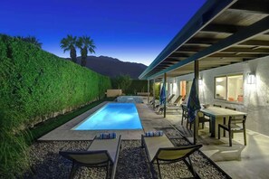 A swimming pool with lounge chairs and a table, surrounded by a hedge and a mountain view. - Alejo Olive Orchard- Beautiful 3 Bed Home with Pool/Spa  - 5 minute drive to downtown Palm Springs. (Palm Springs)
