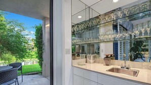 A modern kitchen with a glass backsplash, stainless steel appliances, and a view of a garden. - Beautiful Views-Resort Living (Palm Desert)