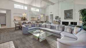 A spacious living room with a large sectional sofa, a glass coffee table, and a dining area with chairs and a table. - Beautiful Views-Resort Living (Palm Desert)